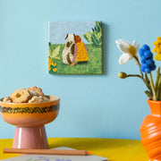 Decoratieve wandtegel van StoryTiles met een 10x10 cm patroon van speelse dieren en planten in natuurlijke kleuren.