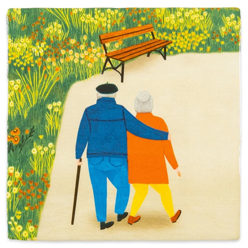 Twee geliefden die hand in hand staan, afgebeeld op een muurkunstwerk van het merk StoryTiles met de tekst 'Couple Goals 10x10'.