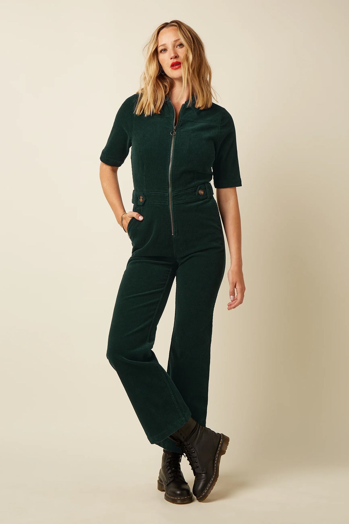 Groene corduroy jumpsuit van King Louie met wijde pijpen en knopen, gedragen door een model.