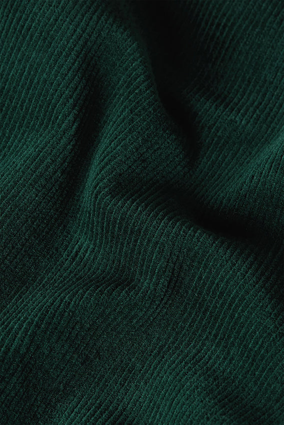 Groene corduroy jumpsuit van King Louie met wijde pijpen en knoopsluiting, gedragen door model op foto.
