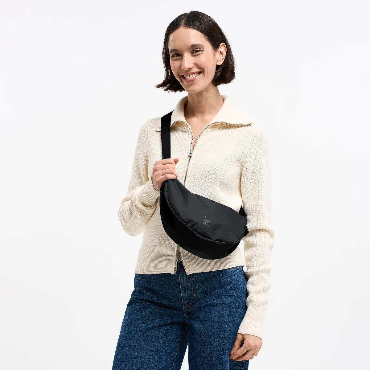 Zwarte kleine Moon Bag van Gotbag met monochroom ontwerp, zichtbaar met ritssluiting en verstelbare schouderband op een effen achtergrond
