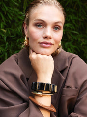 Goudkleurig plat organisch scharnierarmband van Ellen Beekmans, gedetailleerde ronde ontwerp met glanzende afwerking.